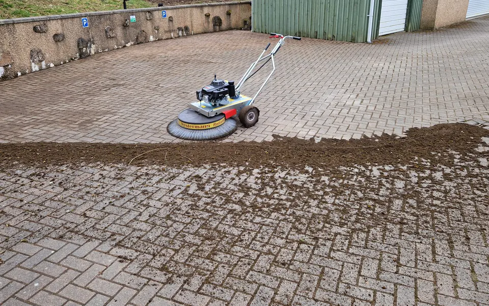 Professional mechanical sweeper clearing debris from block paving